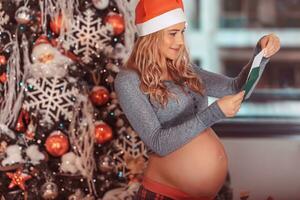 contento embarazada mujer cerca Navidad árbol foto