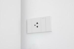 Modern white electrical sockets and light switches on white wall. Plug studio apartment power supply. Light switch. Power outlet. Concept of technology, connection, power saving, energy saving. photo