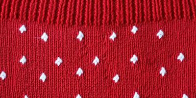 ai generado lana suéter textura de rojo color con blanco punteado. natural de punto lana oscuro rojo color material foto
