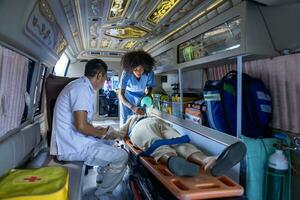 equipo de paramédico es Ayudar el mayor paciente quien es detener respiración desde coche choque por utilizando respirador para corazón ataque y calle accidente foto