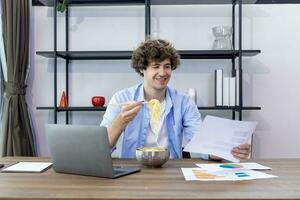 caucásico hombre es trabajando a su hogar oficina mientras comiendo instante fideos y analizando el estadística gráfico para Lanza libre y empresario negocio concepto foto