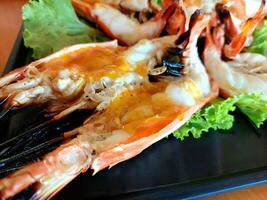 Cutting half grilled giant river prawn, Grilled River Prawns ready for served with chili sauce. famous local Thai luxury fine dinning menu in Thailand. photo