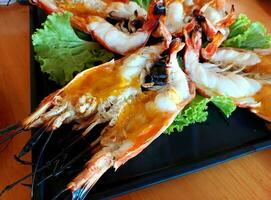 Cutting half grilled giant river prawn, Grilled River Prawns ready for served with chili sauce. famous local Thai luxury fine dinning menu in Thailand. photo