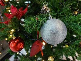 Navidad árbol decorado con Encendiendo. azul y plata Navidad o Navidad pelota adornos colgando en Navidad o pino árbol rama. foto