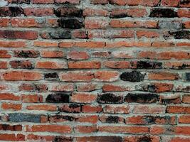 Old weathered brick wall fragment, urban background grunge wall texture Old damaged brick wall with plaster. surface texture of rough orange brick wall with washed out colours. photo