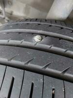 Car wheel that hit the screw nail embedded in the tire. Bolt puncturing tire, selective focus. photo