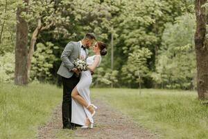 the bride in a white evening dress poses with the groom with a beautiful hairstyle, the groom gently wraps the bride and leans against her. Portrait photo