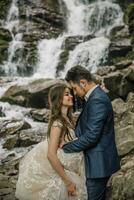 Portrait of a happy bride and groom near a waterfall. Bride and groom. Wedding photo session in nature. Photo session in the forest of the bride and groom.