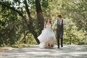 Groom and bride in the garden. Spring wedding in the park. Happy wedding couple running in the park. Stylish and beautiful. Princess dress. photo