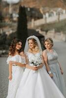Stylish bridesmaids have fun with the bride in nature and pose and look at the bride photo