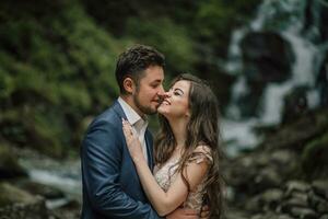 Portrait of a happy bride and groom near a waterfall. Bride and groom. Wedding photo session in nature. Photo session in the forest of the bride and groom.