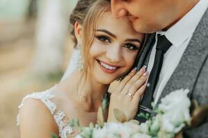 bride and groom on the background of a fairy-tale forest. Royal wedding concept. the groom embraces the bride. Tenderness and calmness. Bride's smile photo