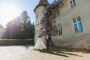 the bride and groom run against the background of the castle in spring flowers and beautiful light. An incredible couple photo
