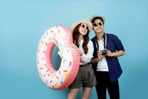 Adorable Asian couple in casual summer clothes and beach floats on light blue background. photo