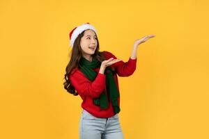 Cheerful asian woman wearing christmas themed attire with arms raised to empty space aside photo