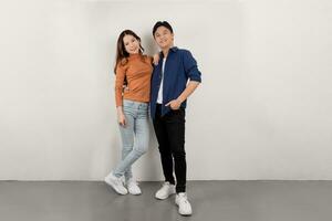 Full length portrait of cheerful young Asian couple in casual outfits smiling and spouses posing and smiling together photo