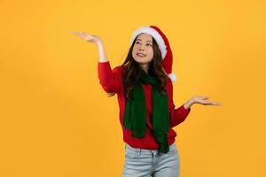 asiático mujer largo pelo estilo vestir rojo suéter, bufanda y Papa Noel sombrero en un amarillo estudio antecedentes. foto