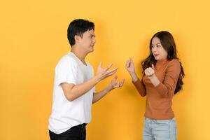 Arguing Asian couple isolated on yellow background. photo