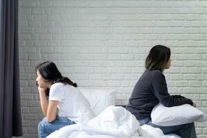 Sad or depressed woman sitting on bed with her couple. Lesbian couple relation problem concept photo