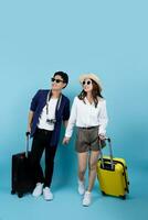 Happy Asian tourists with suitcases enjoying summer vacation together on blue background. photo