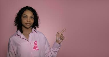 Breast cancer awareness month. banner with girl pointing at empty space. photo