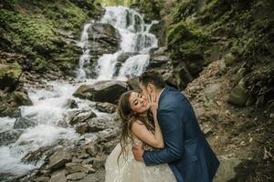 retrato de un contento novia y novio cerca un cascada. novia y novio. Boda foto sesión en naturaleza. foto sesión en el bosque de el novia y novio.