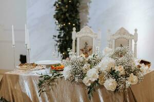 Wedding table serving. Wedding luxury decor. Wedding presidium for the newlyweds. Beautiful decor with pastel roses, candles and greenery. Indoors photo