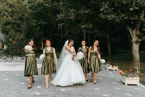 Beautiful bride and her friends- bridesmaids having fun after wedding ceremony. Happy girls at their best friend's wedding. Beautiful and elegant bride with bridesmaids walking on the stairs photo