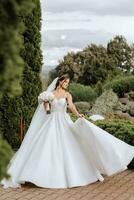 hermosa novia con Boda flores ramo, atractivo mujer en Boda vestido. contento recién casado mujer. novia con Boda maquillaje y peinado. sonriente novia. Boda día. maravilloso novia. casamiento. foto