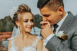 the bride and groom against the background of the sky. Royal wedding concept. The groom kisses the bride's hand. Tenderness and calmness. Portrait photography photo