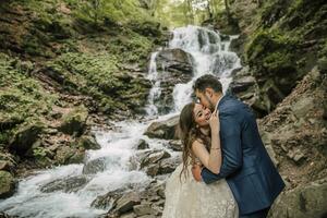 Portrait of a happy bride and groom near a waterfall. Bride and groom. Wedding photo session in nature. Photo session in the forest of the bride and groom.