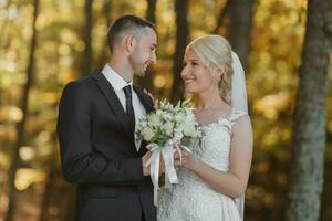 Portrait of the bride and groom in nature. Full size photo. The bride and groom are posing, hugging and smiling, against the background of the autumn forest. The bride in a long dress. photo