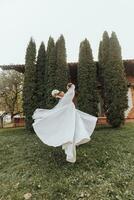 Handsome groom carrying a beautiful laughing bride in his arms in a spring park. The groom is circling with the bride in his arms photo