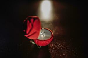 Silver engagement ring of the bride with a precious stone in a red box stands on a table in contour light. Photo of wedding details.