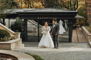 the bride and groom walk in the courtyard of the restaurant near the reception. The groom leads the bride. Stylish and in love brides photo