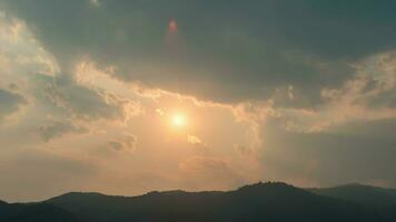 tempo periodo di il sole ambientazione al di sopra di colline quello siamo coperto con nuvole, nel il stile di smokey sfondo. video