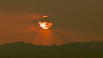 Zeit Ablauf von ein groß Orange Sonne setzt auf ein Berg. video