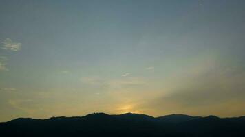 tempo periodo di il sole ambientazione al di sopra di colline quello siamo coperto con nuvole, nel il stile di smokey sfondo. video