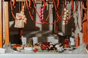 Buffet table at the wedding. An assortment of snacks on white plates standing on a Ukrainian-style tablecloth. Banquet service. Food, snacks with cheese, ham, prosciutto and greens. photo