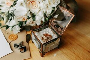 Accessories for the groom's wedding. Luxurious bouquet of the groom. Golden wedding invitation, golden rings, cufflinks on wooden floor background. Men's fashion photo