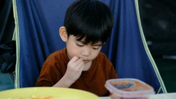 pequeño asiático chico sentado y comiendo francés papas fritas video