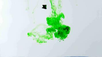 Green ink spreads in the water on a white background. video