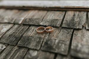 A pair of gold rings on a wooden background. Rustic wedding rings with a matte surface. Jewelry for nature lovers photo