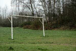 poorly maintained soccer pitch with old soccer goal in the rain photo