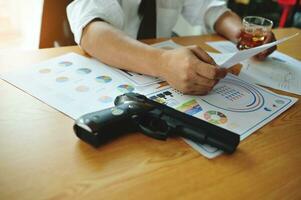 Businessman with charts, alcohol and gun, financial problems Stressful gambling addicts are experiencing financial problems and bankruptcy. photo