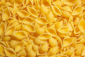 sin cocer conchiglie pasta. un culinario lona de conchiglie macarrones, creando un animado y texturizado antecedentes para gastrónomo cocinando. seco pasta. crudo macarrones - parte superior vista, plano laico foto