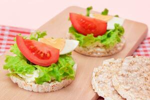 Rice Cake Sandwiches with Tomato, Lettuce and Egg on Wooden Cutting Board. Easy Breakfast. Diet Food. Quick and Healthy Sandwiches. Crispbread with Tasty Filling. Healthy Dietary Snack photo