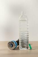 Dumbbells and drinking water in a plastic water bottle. photo
