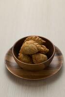 Thai-style curry puff in a dark brown wooden bowl. photo