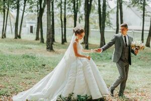 el novia y novio caminar mano en mano mediante el bosque. contento Pareja. Boda foto. Pareja en amor. alto árboles, gran angular foto. Perfecto ligero foto